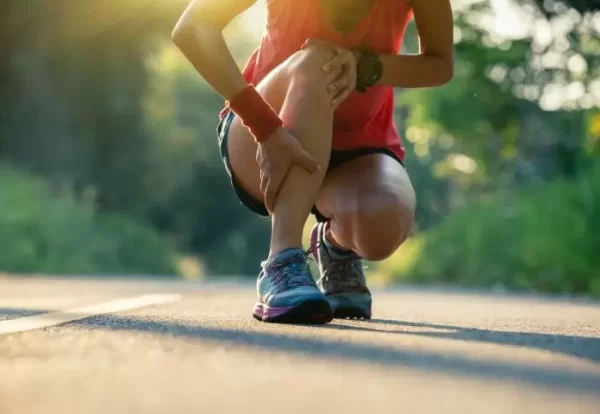 Runner holding leg due to sports injury – Managing Sports Injuries at Home with expert advice from Dr. Ashutosh Jadhav, Orthopedic Doctor in PCMC, Pune