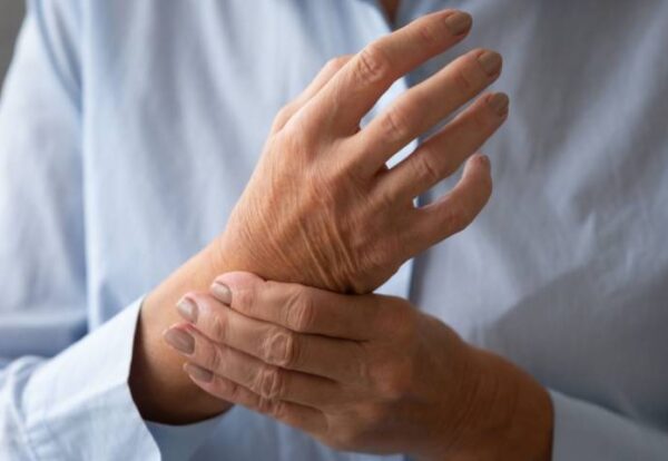 Elderly person holding a painful wrist showing joint stiffness during cold weather, focused on Winter Care for Arthritis & Joint Disorders